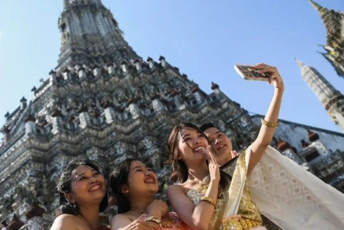 Khách Việt mặc đồ truyền thống của Thái và chụp ảnh tại chùa Wat Arun. Ảnh: Reuters