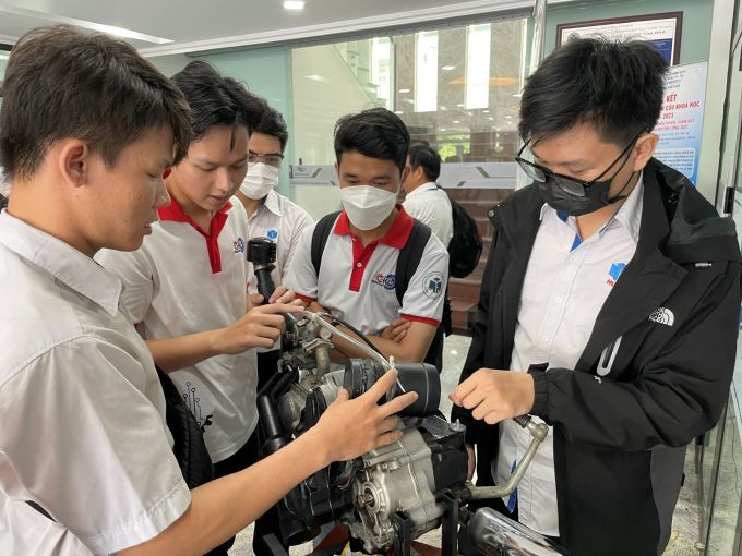 Trần Lê Phước (trái) giới thiệu hệ thống chống ngập tích hợp vào xe máy với các sinh viên cùng trường. Ảnh: Hà An