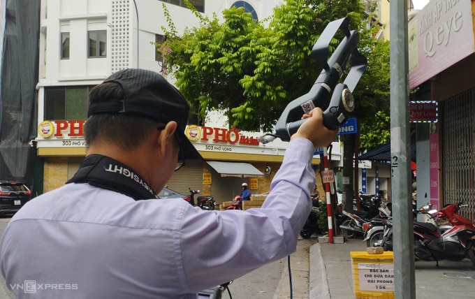Cán bộ Cục Tần số vô tuyến điện dùng thiết bị kiểm tra ở phố Vọng, chiều 22/6. Ảnh: Việt An