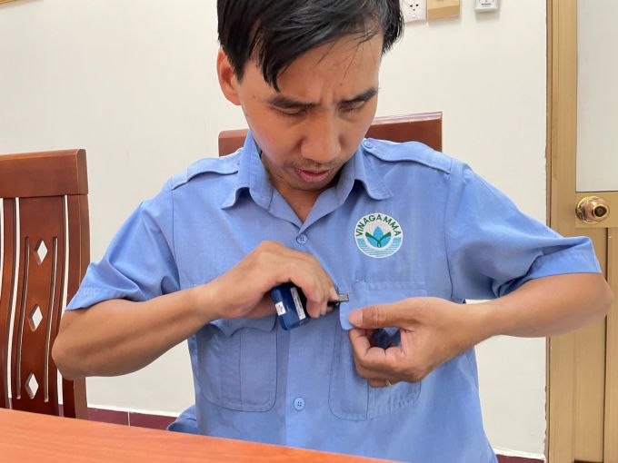 Anh Phan Phước Thắng mang thiết bị đo liều phóng xạ khi làm việc ở cự ly gần máy chiếu xạ tại Vinagamma. Ảnh: Hà An