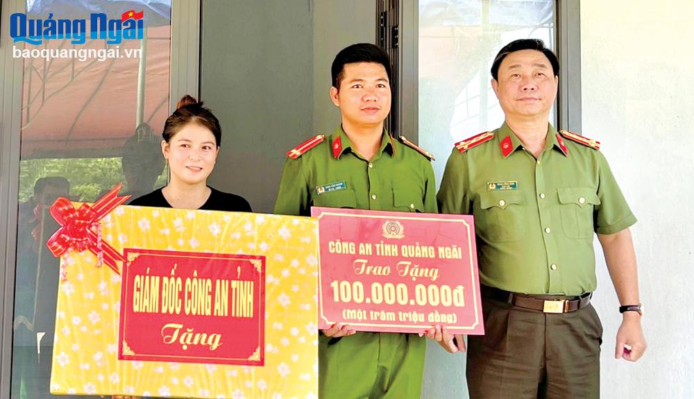 Đại tá Phan Công Bình - Giám đốc Công an tỉnh trao bảng tượng trưng hỗ trợ 100 triệu đồng và quà cho gia đình Trung úy Đinh Văn Thanh.
