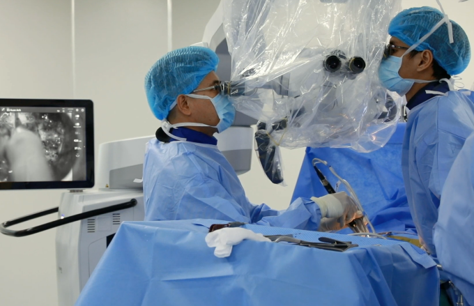 Bác sĩ Xuân Anh (trái) sử dụng kính vi phẫu trong một ca phẫu thuật bệnh thần kinh cột sống. Ảnh: Bệnh viện Đa khoa Tâm Anh