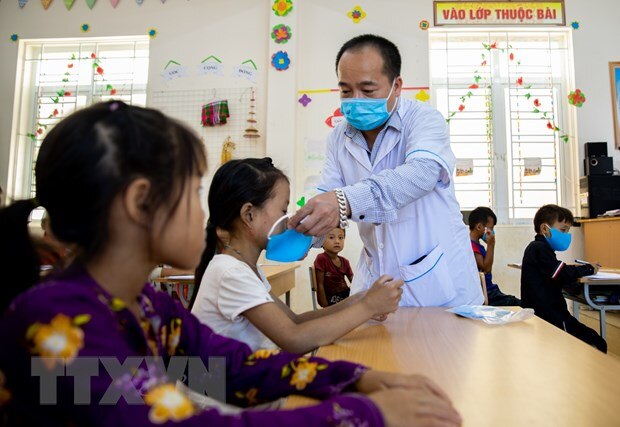 Cán bộ y tế phát khẩu trang cho các em học sinh tại Trường Phổ thông dân tộc bán trú Tiểu học xã Khâu Vai, Mèo Vạc, Hà Giang). (Ảnh: Nam Thái/TTXVN)