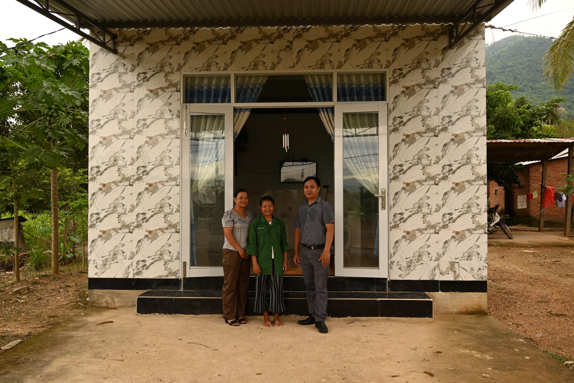 Chị Hương cùng cán bộ xã, thôn bên căn nhà mới xây