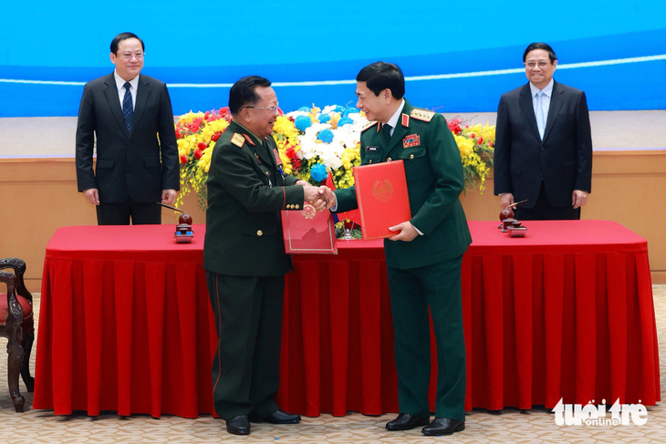 Thúc đẩy làm đường cao tốc, đường sắt nối Việt Nam và Lào- Ảnh 4. Hai Thủ tướng chứng kiến lễ ký kết và trao văn kiện hợp tác giữa hai Bộ Quốc phòng - Ảnh: NGUYỄN KHÁNH