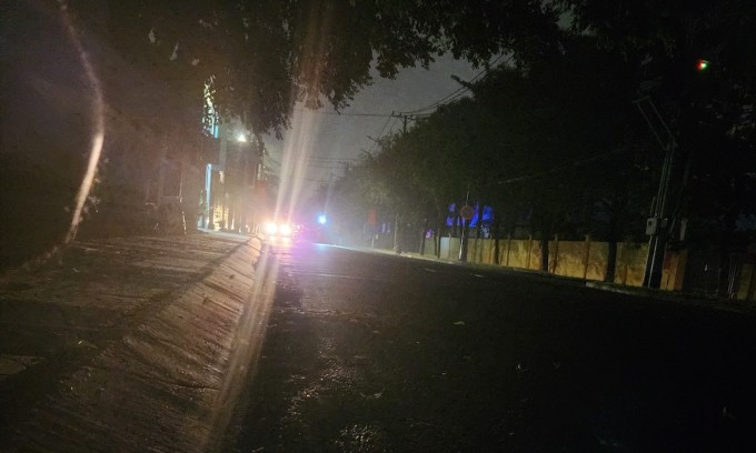 Cảnh sát phong toả tuyến đường trước trụ sở Công an quận 12, người dân, phương tiện được lực lượng chức năng rọi đèn pin hướng dẫn đi đường khác. Ảnh: Đình Văn