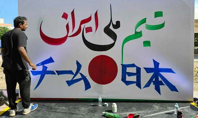 Một nghệ sĩ viết chữ Iran và Nhật Bản ngoài sân Education City. Ảnh: Reuters