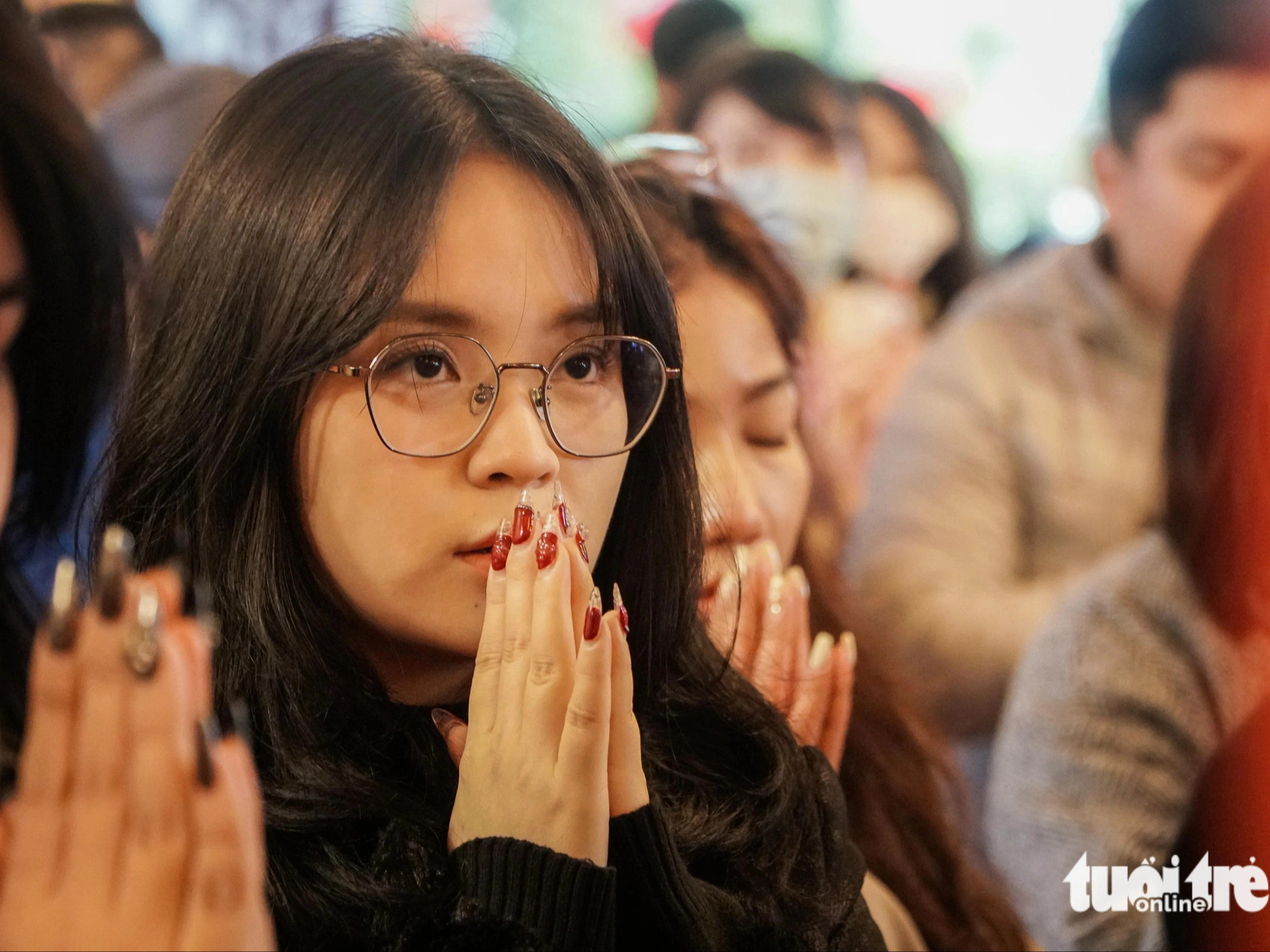 Hàng ngàn người đội mưa rét đến phủ Tây Hồ lễ rằm tháng giêng- Ảnh 5. Một bạn trẻ đang thành tâm cầu nguyện - Ảnh: PHẠM TUẤN