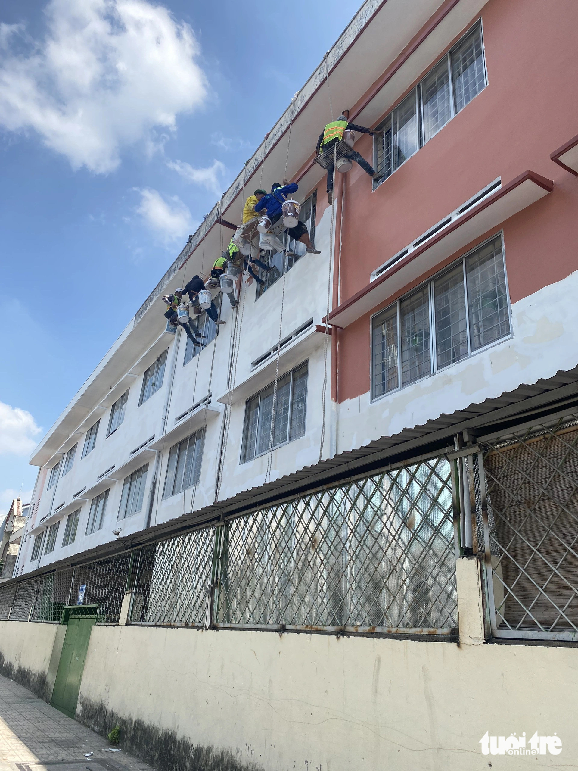 Trường thi công sửa chữa, trò học giữa bụi bặm, ồn ào- Ảnh 4. Đội ngũ thi công đang sơn sửa bên ngoài Trường tiểu học Trần Văn Vân - Ảnh: NGỌC PHƯỢNG