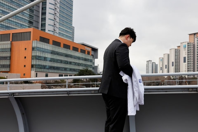 Bác sĩ Ryu O. Hada, 25 tuổi, một trong những người đình công, cởi bỏ tấm áo blouse tại một bệnh viện ở Seoul, ngày 25/2. Ảnh: Reuters