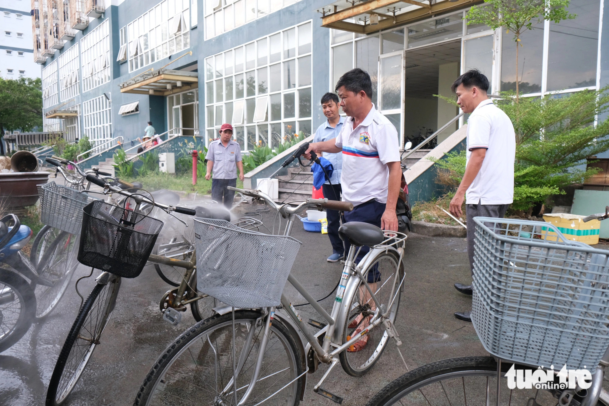 Cán bộ ký túc xá sửa xe đạp gửi tặng trẻ em khó khăn- Ảnh 1. Cán bộ nhân viên Trung tâm quản lý ký túc xá Đại học Quốc gia TP.HCM rửa lại những chiếc xe đạp cũ để gửi trao đến trẻ em khó khăn - Ảnh: NGỌC PHƯỢNG