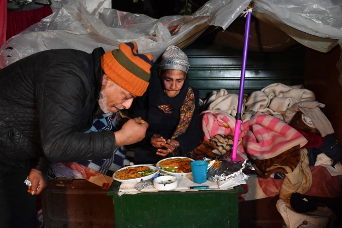 Bà Leila (phải) cùng một người vô gia cư khác thưởng thức bữa ăn mà Nhà hàng tình yêu cung cấp ở thủ đô Tunis, Tunisia ngày 26/1. Ảnh: AFP