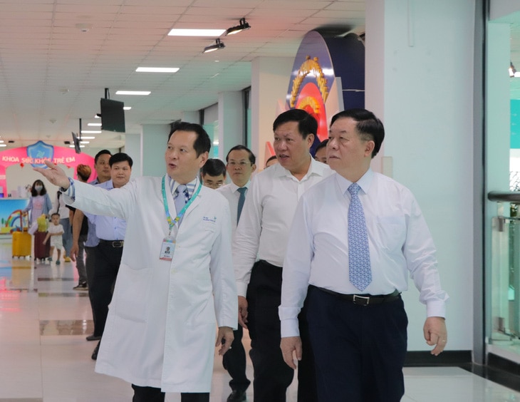 Giám đốc Bệnh viện Nhi đồng TP.HCM (trái) đưa đoàn đại biểu tham quan cơ sở vật chất của bệnh viện - Ảnh: CẨM NƯƠNG