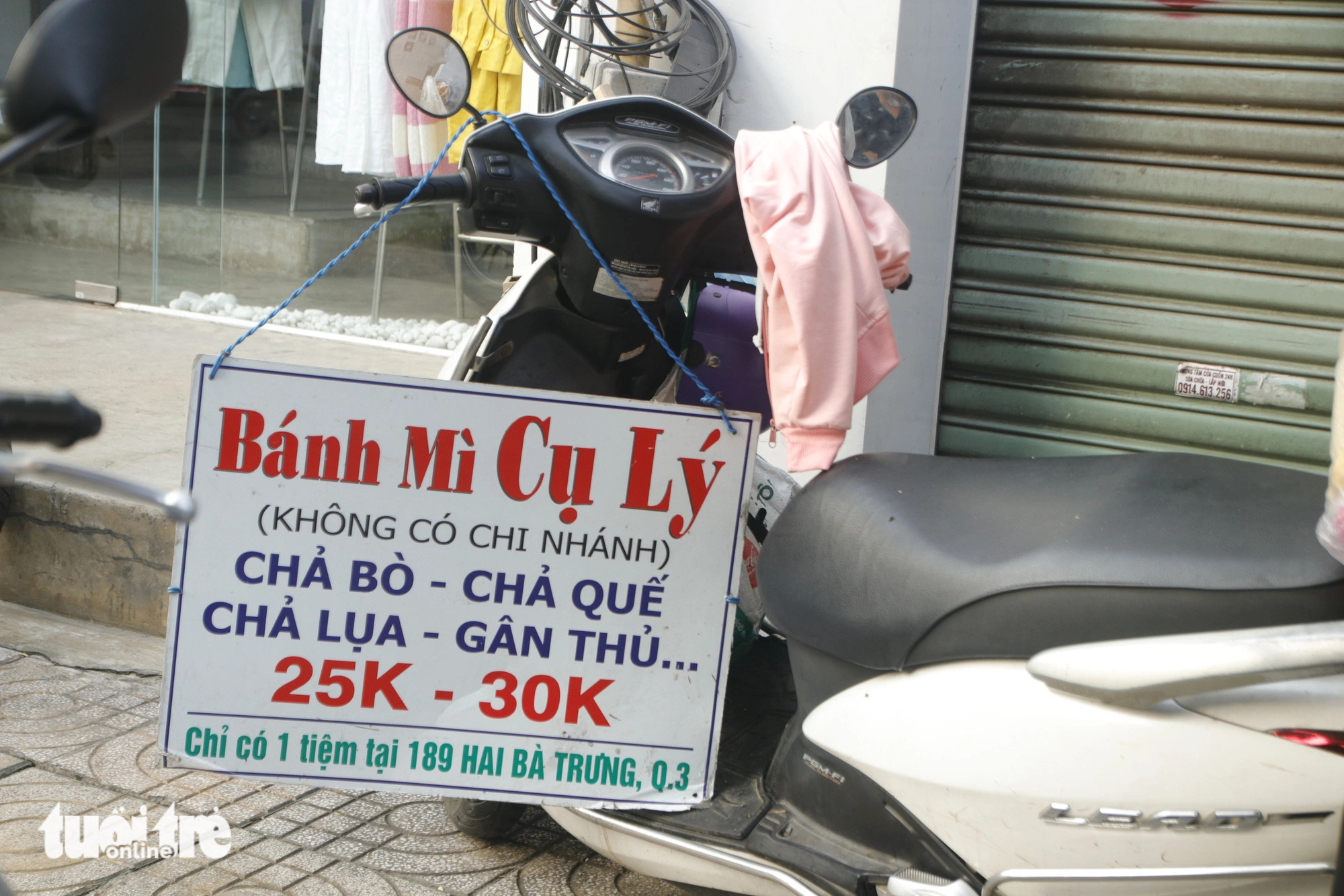 Bảng hiệu bánh mì cụ Lý được treo giản dị trên một chiếc xe máy. Đó cũng là chiếc xe anh chở giò chả đến bán mỗi ngày Bảng hiệu bánh mì cụ Lý được treo giản dị trên một chiếc xe máy. Đó cũng là chiếc xe anh Thiện chở giò chả đến bán mỗi ngày