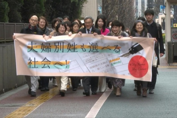 Các đôi vợ chồng giơ khẩu hiệu yêu cầu vợ và chồng được giữ họ của bản thân trước tòa án Tokyo ngày 8/3. Ảnh: AFP