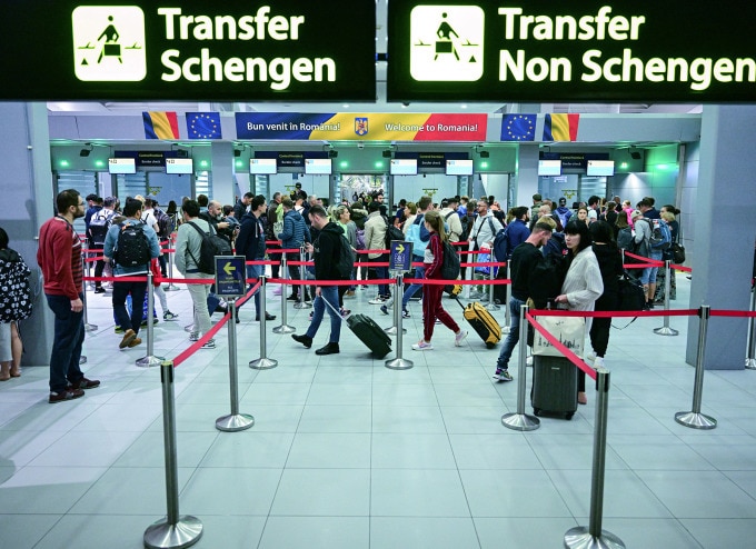 Du khách đi cạnh các biển báo mới được lắp đặt quy định khu vực Schengen và không thuộc Schengen tại sân bay lớn nhất Romania, Henri Coanda, rạng sáng 31/3 ngay sau khi nước này gia nhập khối. Ảnh: AFP