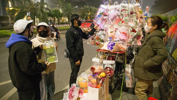 Một số khách đến xem các bó hoa đan, móc bằng len tự làm tại một xe hàng trên đường Yên Phụ, quận Tây Hồ, tối 4/3. Ảnh: Thanh Nga