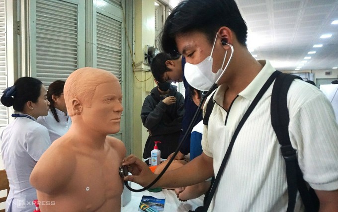 Học sinh trải nghiệm nghe nhịp tim thông qua mô hình tại ngày hội, sáng 14/4. Ảnh: Lệ Nguyễn
