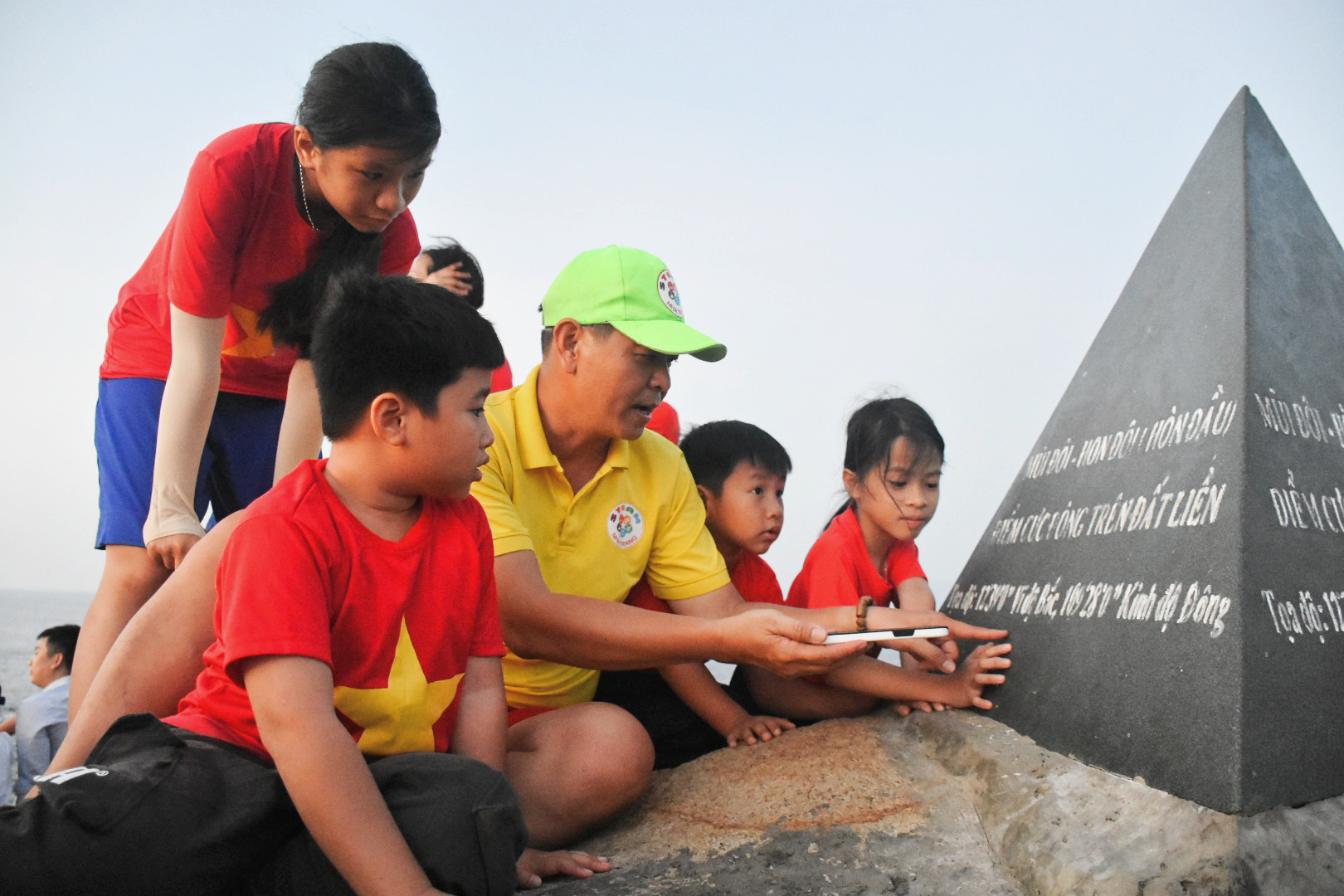 Đón bình minh sớm nhất ở Mũi Đôi cực đông đất liền bằng đường bộ - Ảnh 10. Các em nhỏ được giới thiệu về tọa độ, thông tin trên cột mốc cực Đông đất liền Tổ quốc - Ảnh: TRẦN HOÀI