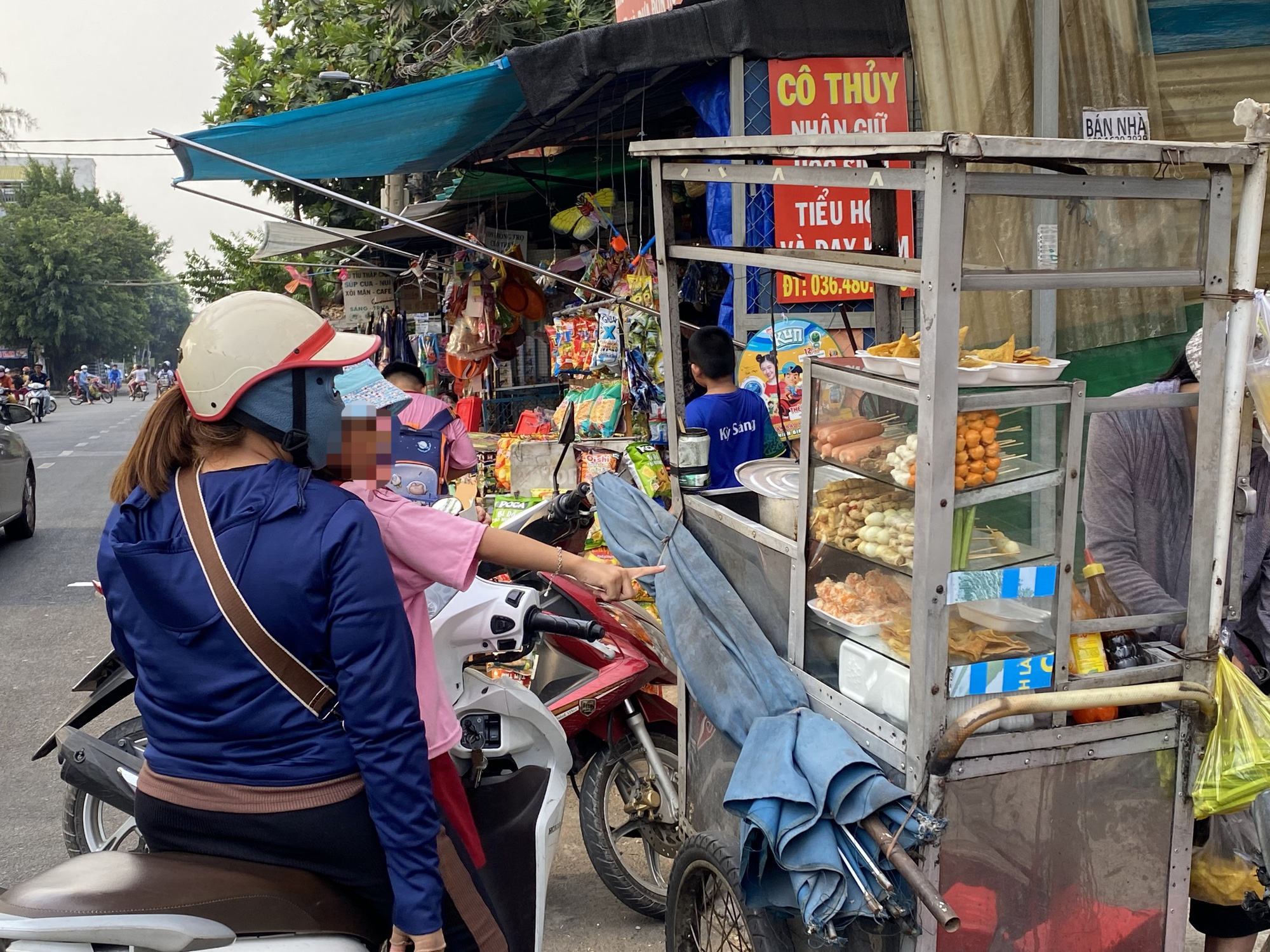 Hàng rong nhan nhản trước cổng trường ở TP.HCM, không chỉ học sinh mà phụ huynh cũng mua- Ảnh 2. Phụ huynh mua đồ ăn vặt cho con vào giờ ra về trước cổng trường tiểu học - Ảnh: VŨ HIÊN