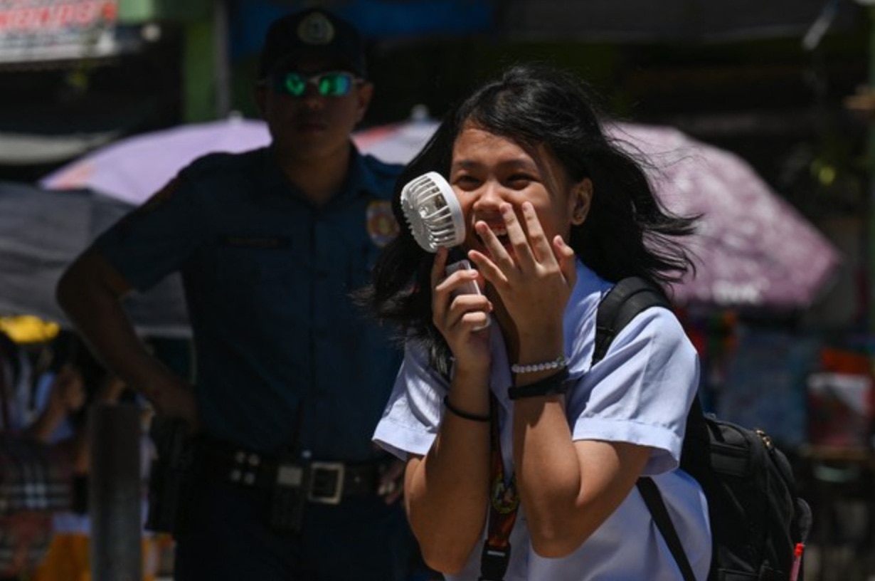 Một học sinh tại thủ đô Manila đang cầm quạt bên ngoài cổng trường giữa thời tiết nắng nóng tháng 4 - Ảnh: AFP