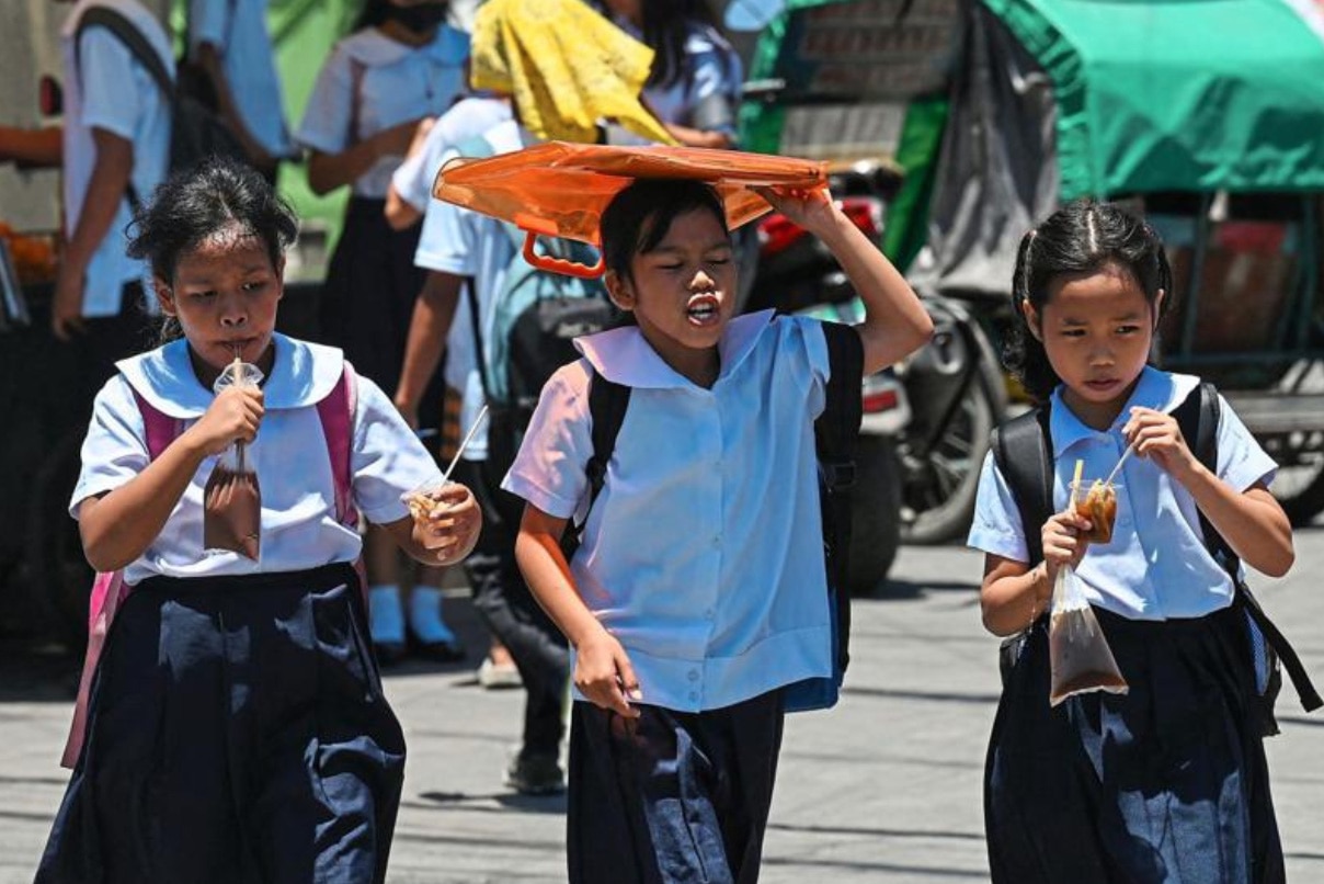Một học sinh dùng túi che nắng sau giờ tan học tại thủ đô Manila tháng 4-2024 - Ảnh: AFP