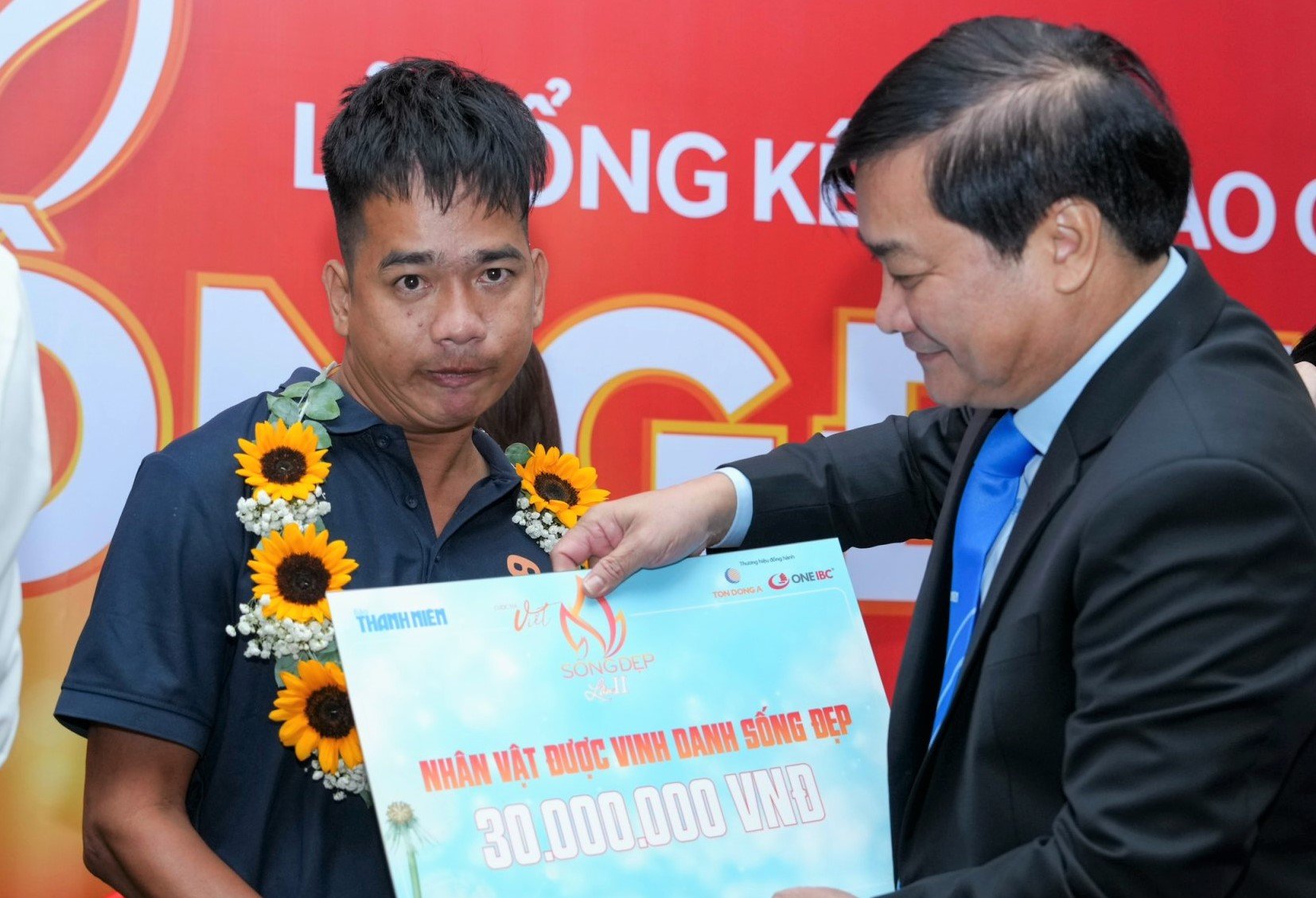 Đề kiểm tra ngữ văn lan tỏa tinh thần 'Sống đẹp' từ cuộc thi Báo Thanh Niên- Ảnh 3. Anh Quảng Đình Hậu, nhân vật trong tác phẩm Vòng xe của Hậu, nhận giải Nhân vật được vinh danh Sống đẹp (30 triệu đồng) từ Trưởng ban tổ chức cuộc thi, Tổng biên tập Báo Thanh Niên Nguyễn Ngọc Toàn