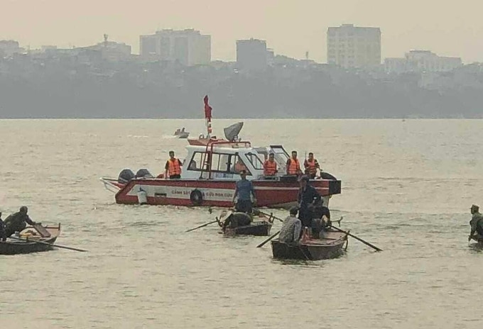 Cảnh sát cứu nạn cứu hộ và người dân thuyền chài tìm kiếm thi thể hai học sinh. Ảnh: Việt An