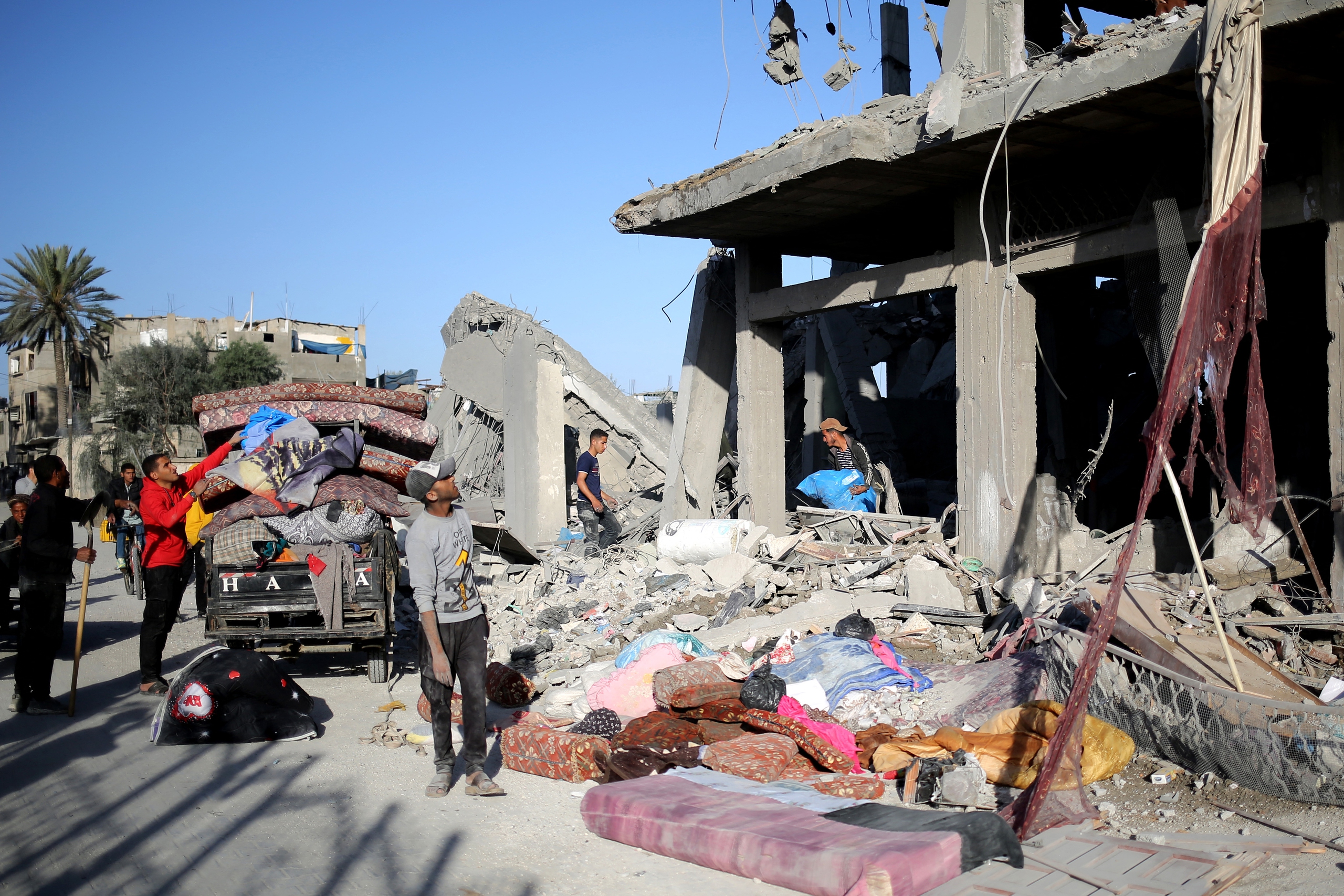 Israel không kích Rafah, Đức điều tàu chiến mới đến biển Đỏ- Ảnh 1. Người dân Palestine nhặt đồ từ một tòa nhà bị Israel tập kích tại thành phố Rafah ở Dải Gaza