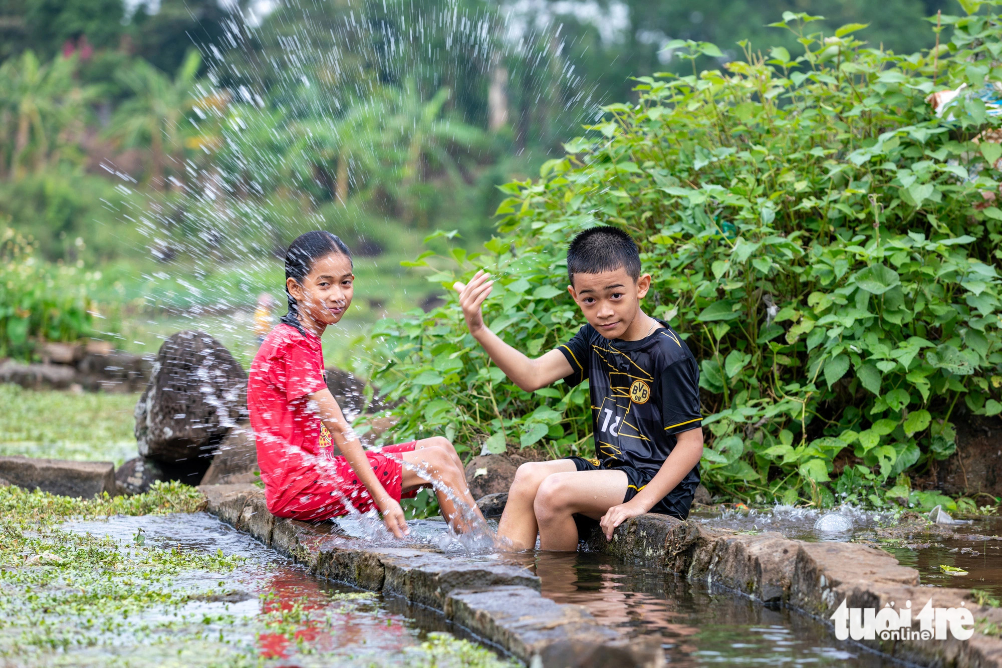 Tắm mát ở giếng cổ 2.000 năm tuổi trong chuỗi ngày nóng kỷ lục miền Trung- Ảnh 1. Trẻ em đến chơi, tắm mát ở các giếng cổ Gio An - Ảnh: HOÀNG TÁO