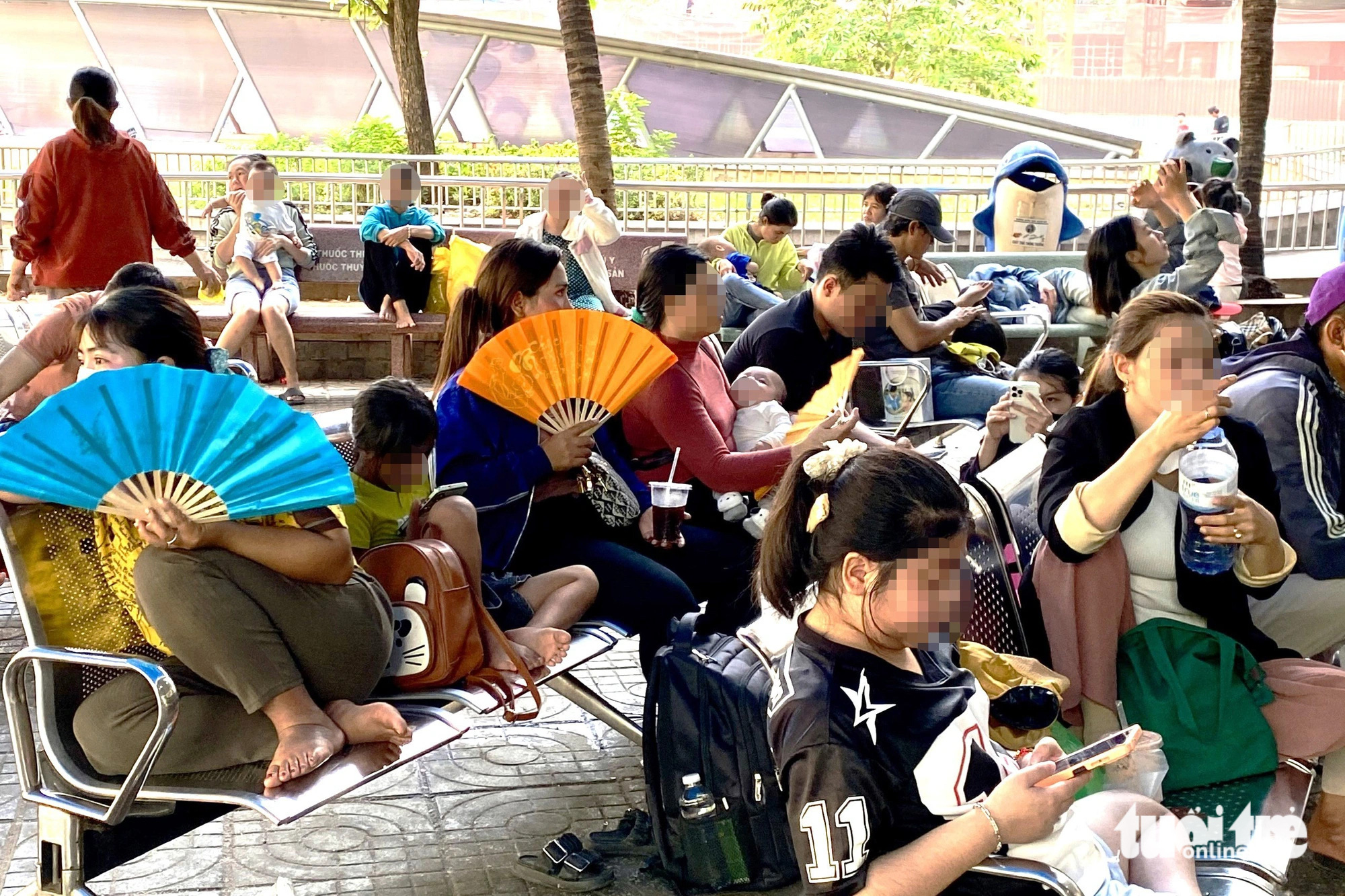 Trẻ bệnh hô hấp, rối loạn tiêu hóa vì nắng nóng tăng- Ảnh 1. Dãy ghế trước khoa khám bệnh Bệnh viện Nhi đồng 2 (TP.HCM) trưa 4-4 có rất đông phụ huynh và trẻ nhỏ ngồi chờ tới lượt khám bệnh. Thời tiết oi bức, nhiều phụ huynh dùng quạt giải nhiệt cho con trẻ - Ảnh: XUÂN MAI