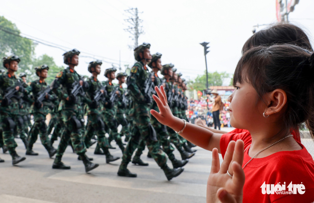 Một bé gái mặc áo hình cờ Tổ quốc vẫy tay chào khối chiến sĩ lục quân khi đi ngang qua một con phố tại Điện Biên - Ảnh NGUYỄN KHÁNH Một bé gái mặc áo hình cờ Tổ quốc vẫy tay chào khối chiến sĩ lục quân khi đi ngang qua một con phố tại Điện Biên - Ảnh NGUYỄN KHÁNH