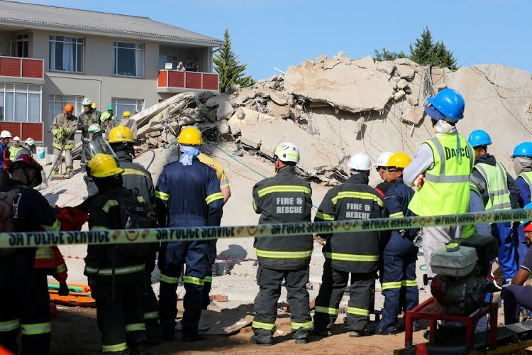 Lực lượng cứu hộ và những người chứng kiến đã đồng loạt reo hò và vỗ tay khi một người sống sót được đưa ra sau 116 giờ từ dưới đống đổ nát của một tòa nhà bị sập ở thành phố George, Nam Phi, trong thảm kịch đã khiến ít nhất 14 người thiệt mạng. (Nguồn: Herald Live)