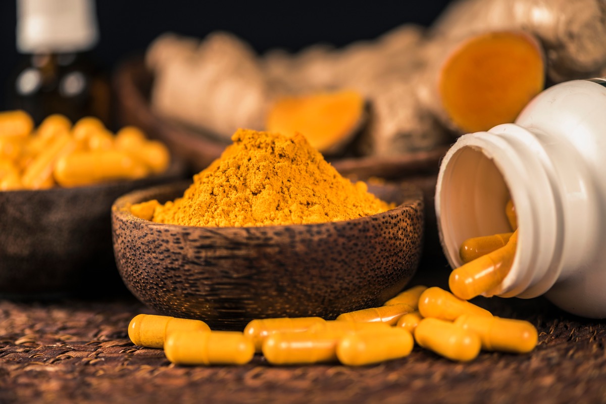 7 chất bổ sung cần tránh nếu bạn đang dùng thuốc giảm cân- Ảnh 3. Viên nang bổ sung curcumin, bột nghệ trong bát thủy tinh và rễ nghệ làm nền.