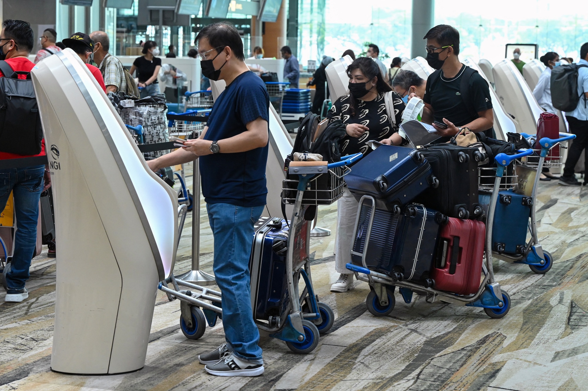 Du khách đeo khẩu trang phòng chống dịch COVID-19 tại sân bay Changi (Singapore) hồi tháng 4-2022 - Ảnh: AFP