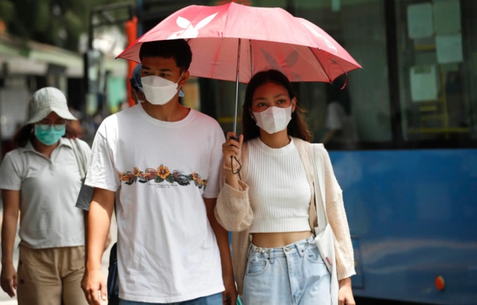 Người dân đeo khẩu trang, mặc áo dài tay chống nắng và che ô khi ra đường tại Bangkok, Thái Lan hồi cuối tháng 4. Ảnh: EFE