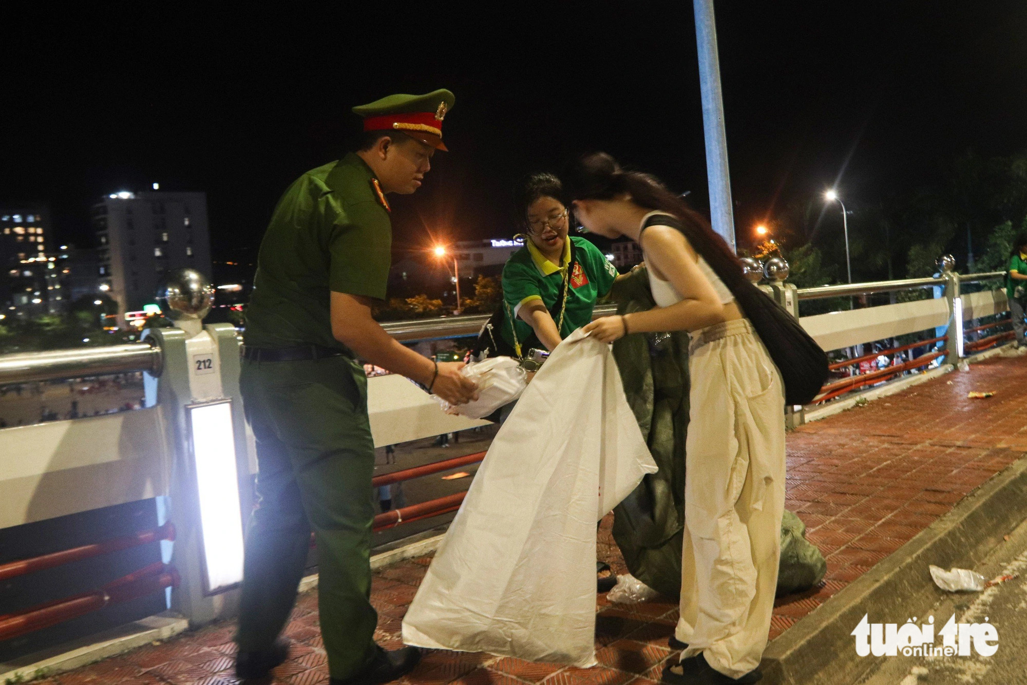 Rác ngổn ngang sau pháo hoa Đà Nẵng, bao giờ hết cảnh người xả người đi dọn?- Ảnh 8. Chiến sĩ công an cùng các bạn trẻ nhặt rác trên cầu Sông Hàn - Ảnh: THANH NGUYÊN