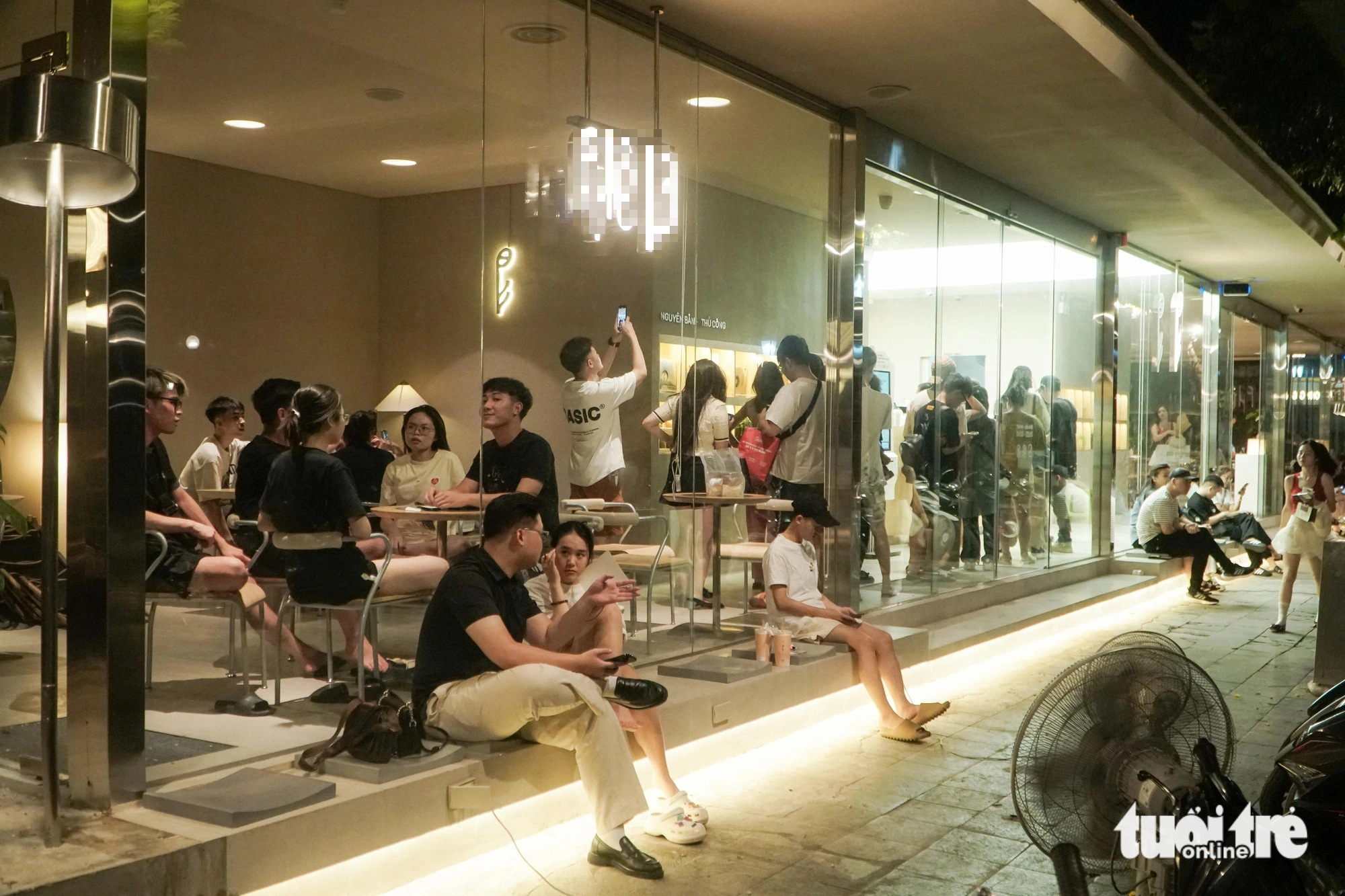 Người trẻ Hà Nội xếp hàng từ 4h sáng để uống cà phê, có người chuẩn bị từ 0h- Ảnh 5. Bên trong người xếp hàng, bên ngoài người ngồi đợi để thưởng thức cà phê lúc 4h sáng - Ảnh: PHẠM TUẤN
