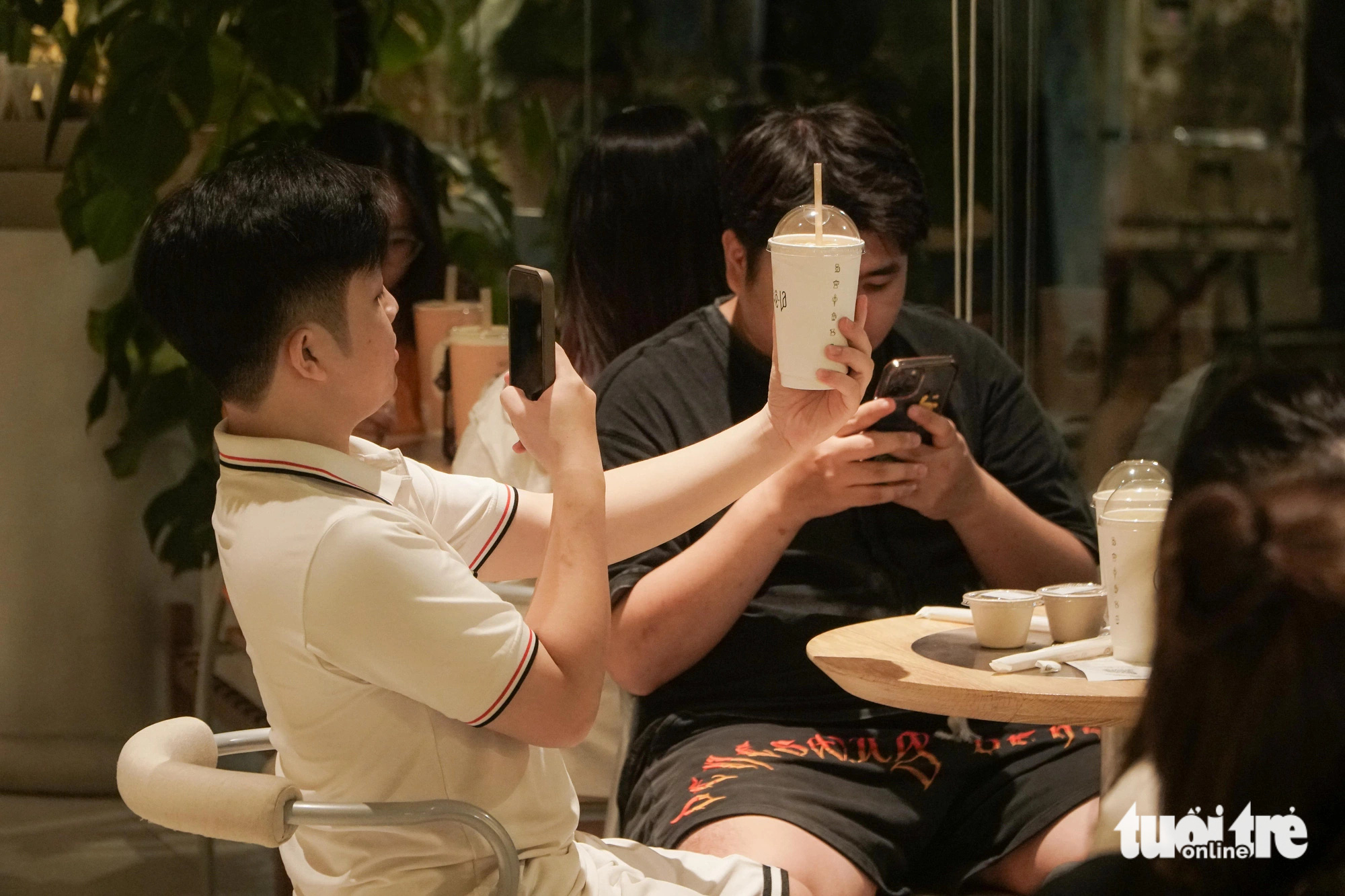 Người trẻ Hà Nội xếp hàng từ 4h sáng để uống cà phê, có người chuẩn bị từ 0h- Ảnh 10. Một bạn trẻ "check-in" với cốc trà sữa vừa order - Ảnh: PHẠM TUẤN