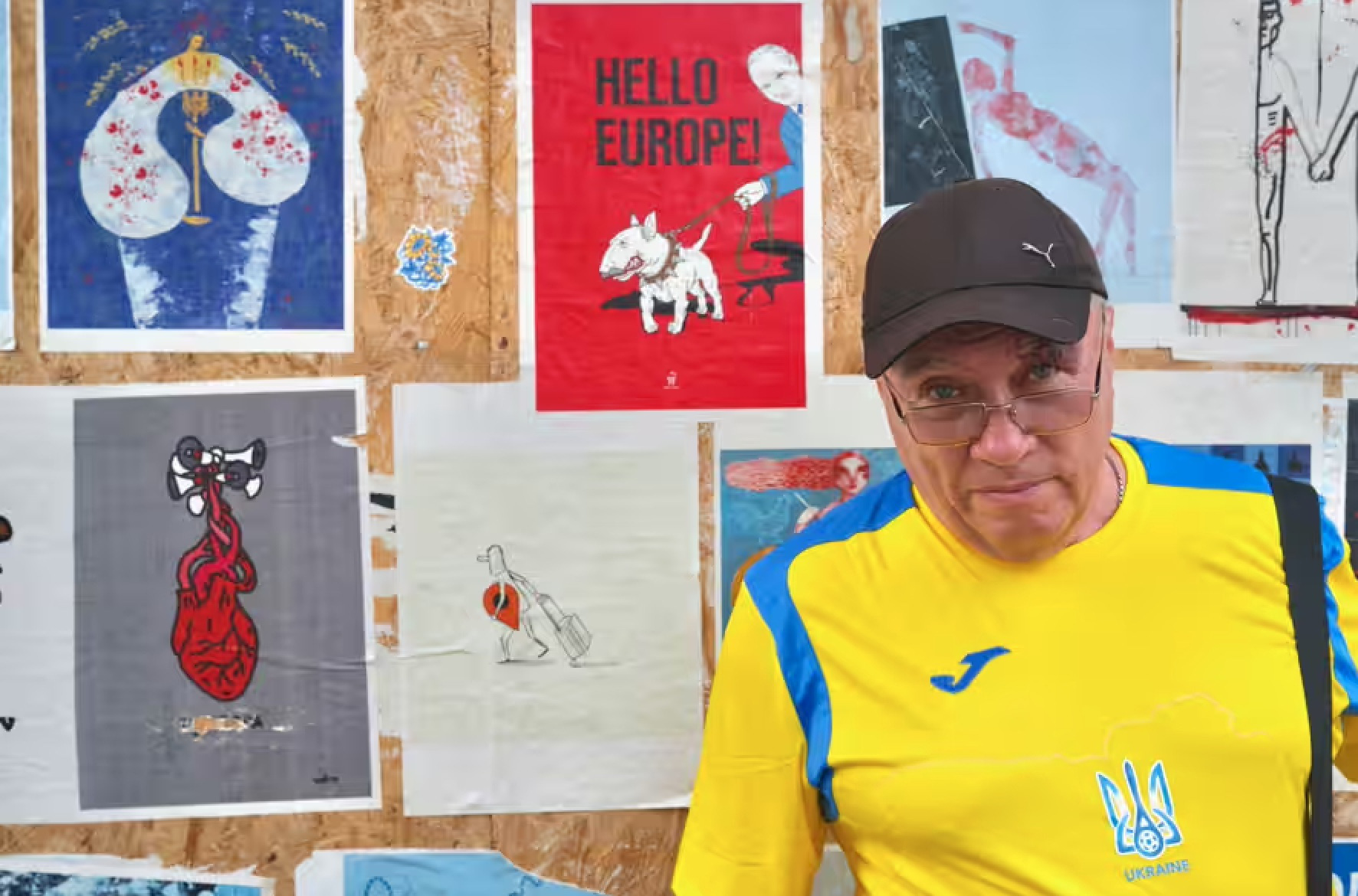 Mặc kệ chiến tranh, người dân Ukraine hòa vào không khí Euro 2024- Ảnh 6. Một du khách đến từ vùng Mykolaiv (Ukraine) mặc áo của đội tuyển Ukraine và chụp hình bên cạnh các bức tranh - Ảnh: RICHARD MORGAN