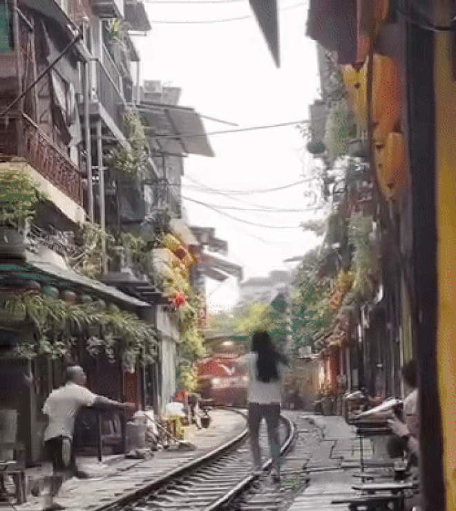 Khách Tây vẫn đến cà phê đường tàu nườm nượp sau vụ cô gái lao ra đường ray chụp ảnh- Ảnh 7. Người đàn ông kịp đẩy cô gái vào phía trong trước khi tàu hỏa tới - Ảnh: HN TV