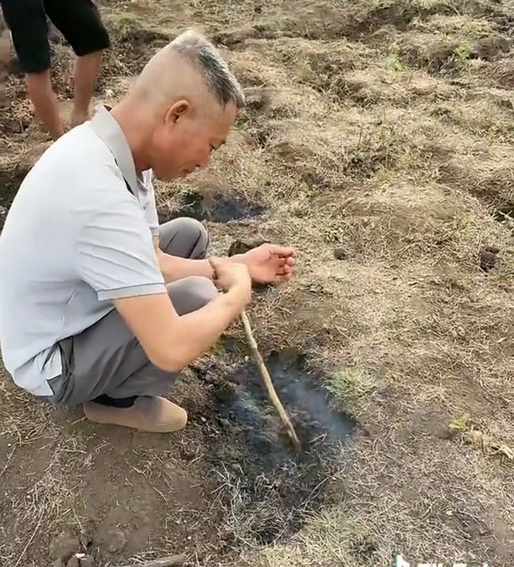 Thực hư mặt ruộng 'tự bốc cháy' kỳ lạ ở cánh đồng Gia Lai- Ảnh 1. Người đàn ông dùng que chọt xuống mô đất đang bốc khói trên cánh đồng xã Bar Măih, huyện Chư Sê, Gia Lai - Ảnh: Tik Tok
