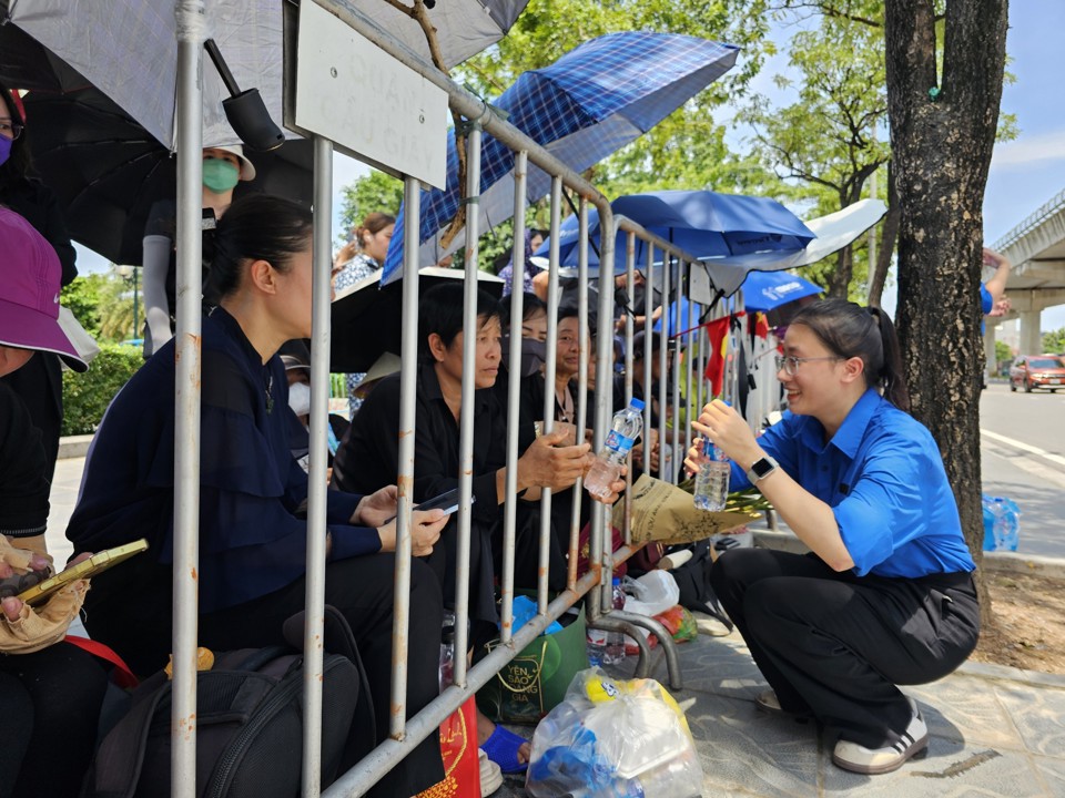 Thanh niên tình nguyện tiếp nước cho người dân chờ tiễn biệt Tổng Bí thư Nguyễn Phú Trọng trên đường Lê Đức Thọ. Ảnh: Quân Thủy