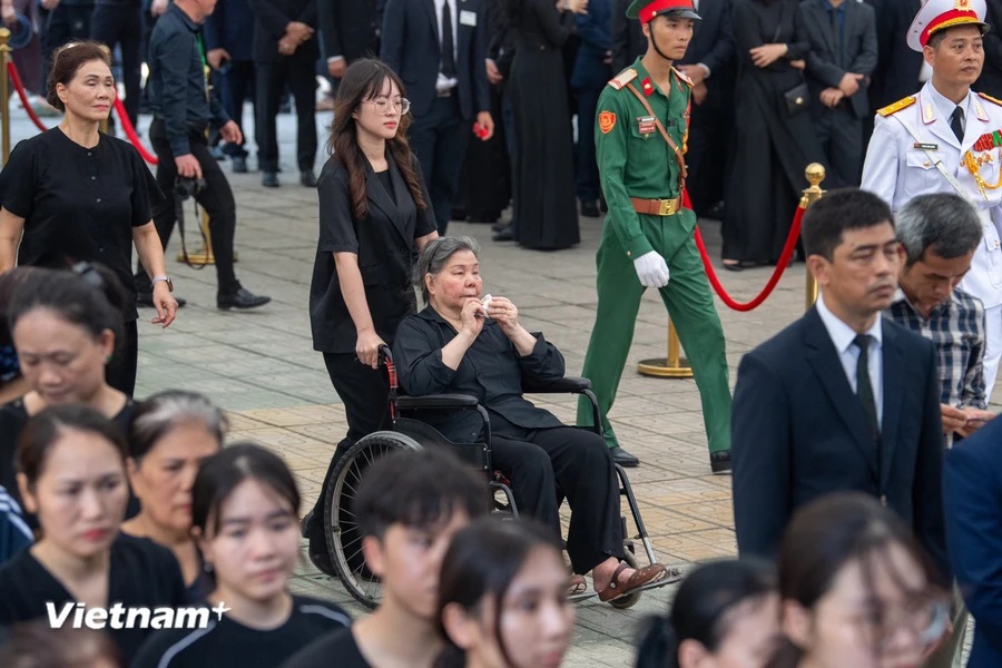 Cô giáo Đặng Thị Phúc ngồi xe lăn được người thân đưa đến viếng Tổng Bí thư Nguyễn Phú Trọng sáng 26/7. Ảnh: TTXVN
