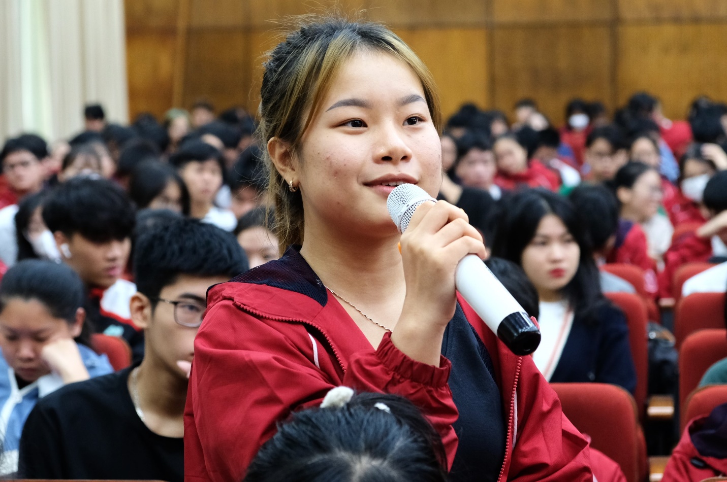 Hơn 800 sinh viên Đại học Bách Khoa Hà Nội giao lưu cùng Tổng Giám đốc Ajinomoto Việt Nam- Ảnh 3. A person holding a microphone in front of a crowd Description automatically generated