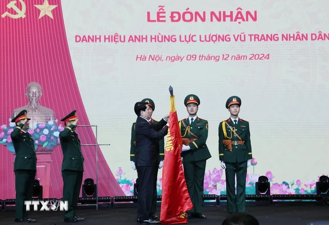 Chủ tịch nước Lương Cường gắn huy hiệu Anh hùng Lực lượng vũ trang nhân dân lên lá cờ truyền thống Viện Hàng không Vũ trụ Viettel. (Ảnh: Lâm Khánh/TTXVN) TTXVN_0912 Chu tich nuoc (10).jpg